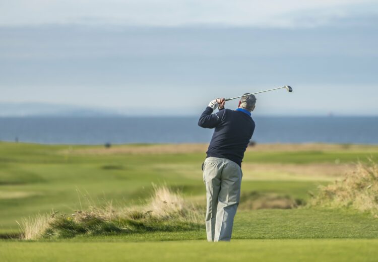 Golfer with a backdrop of a golf course and the ocean.