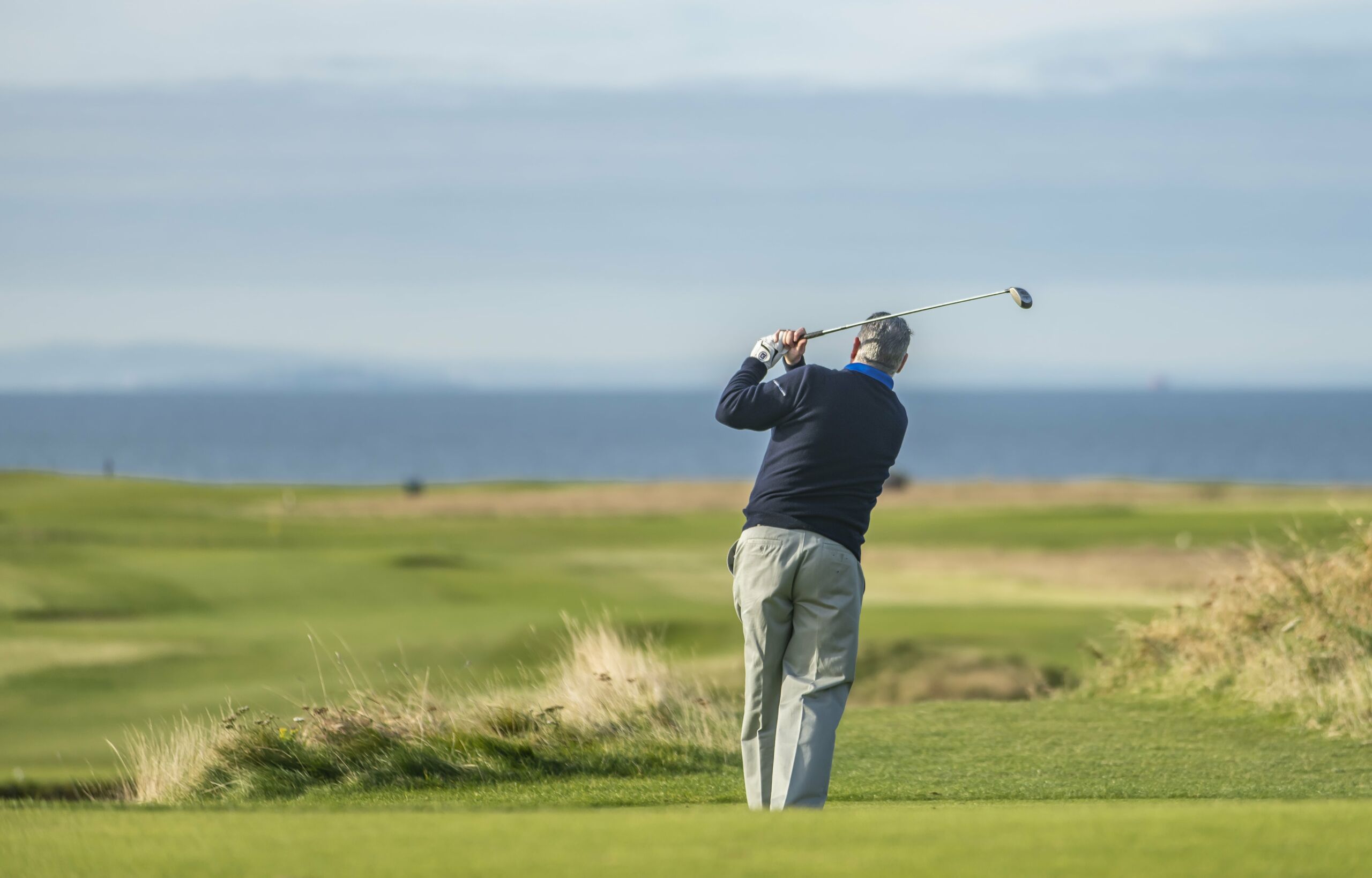 Golfer with a backdrop of a golf course and the ocean.