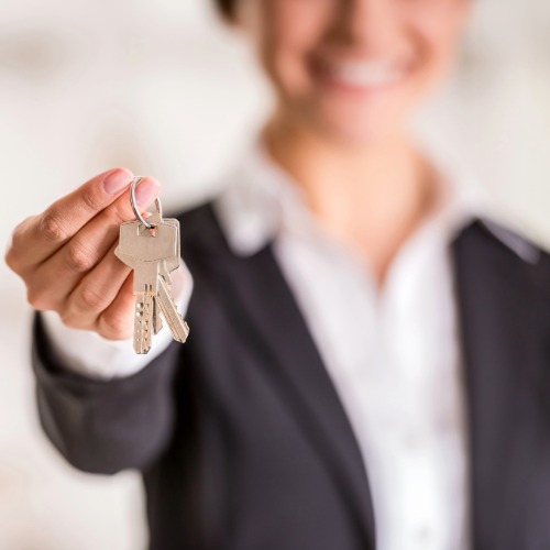 Person holding keys, smiling confidently.